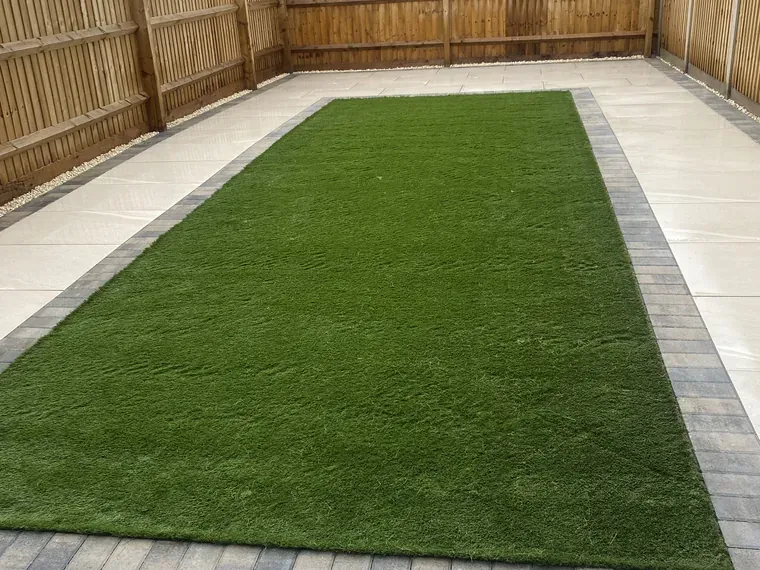 Artificial grass lawn framed by a paved border and new fencing