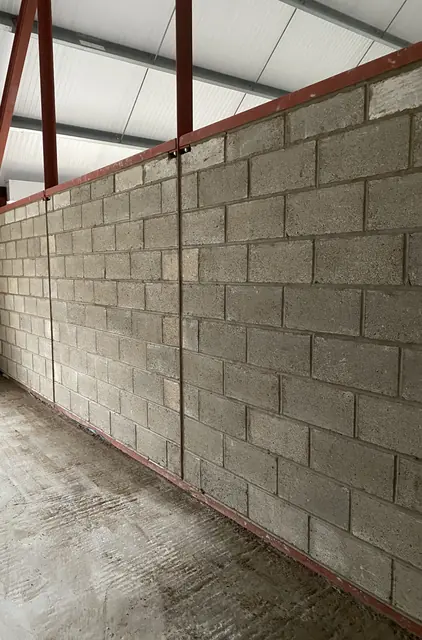 Concrete blockwork wall built inside a steel-framed commercial unit