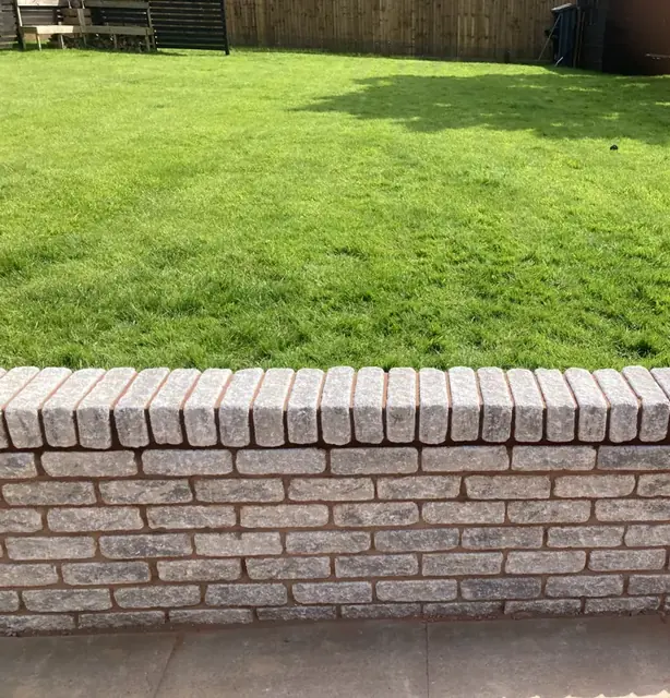 Low brick garden wall finished with a brick-on-edge coping