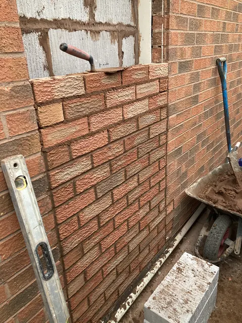 New facing brickwork going up against cavity insulation, matched to the existing house