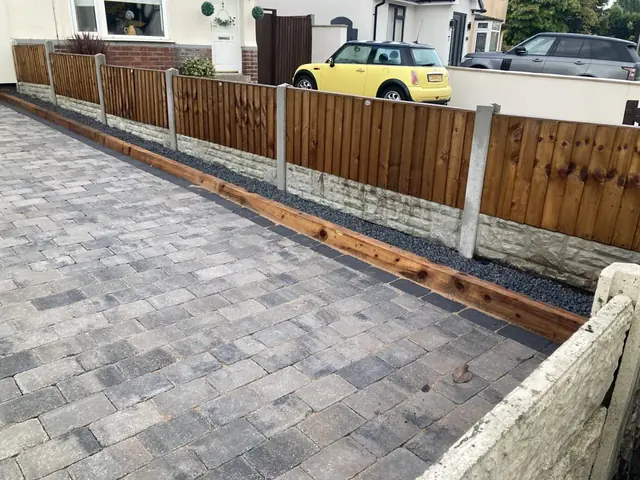 New block paved driveway beside close-board fencing with concrete gravel boards