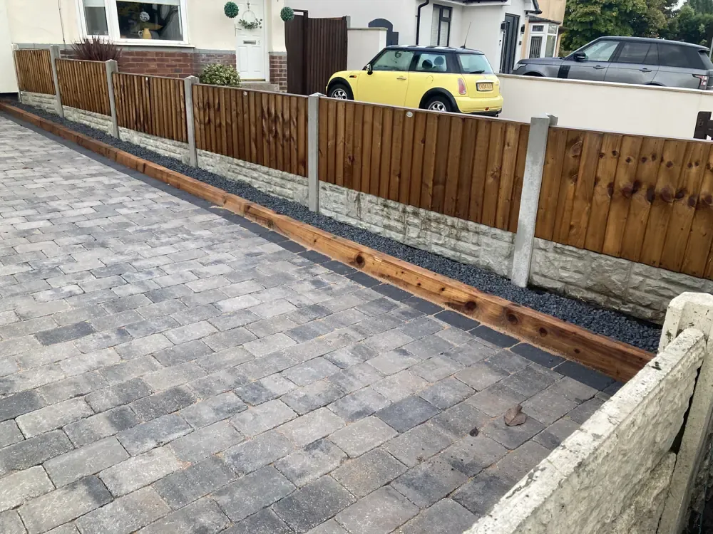 New block paved driveway beside close-board fencing with concrete gravel boards