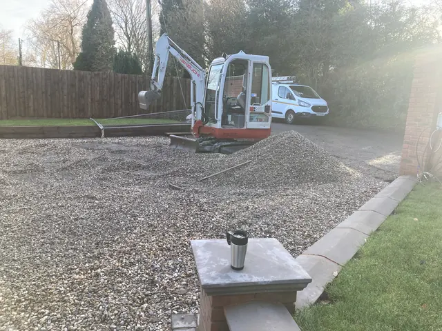 Gravel driveway going down beside a capped brick pier and kerb edging