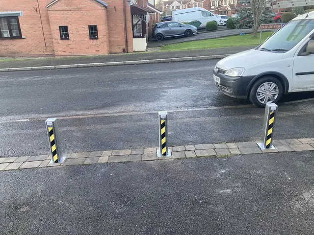 Three fold-down driveway security posts set into a block paved strip