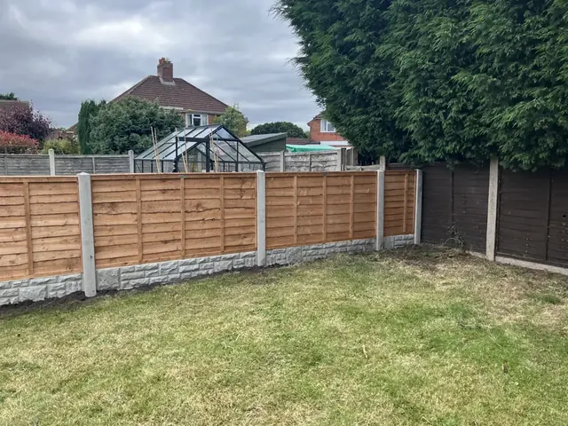 Lap panel fence on concrete posts along a back garden lawn