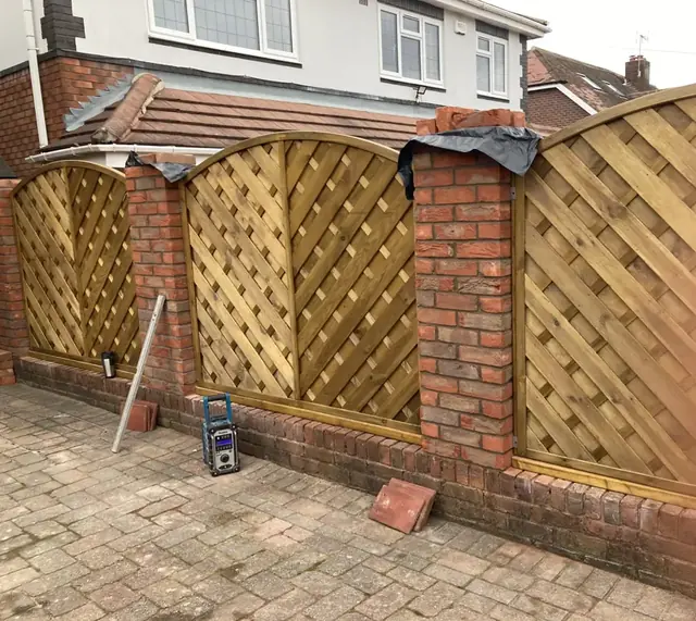 Curved lattice fence panels set between red brick piers
