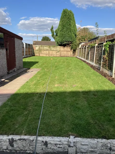 New turf laid along a long back garden beside a slabbed path