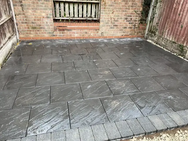 Dark grey riven slab patio with a block paving edge