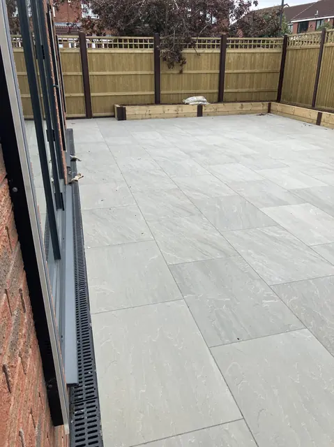 Grey porcelain patio with a linear drainage channel running along the bifold doors
