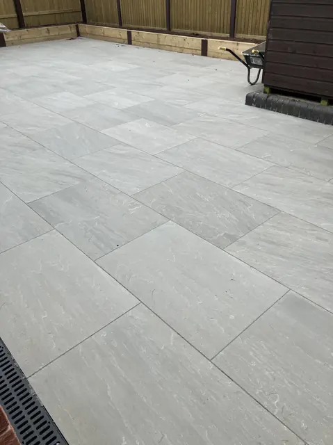 Grey porcelain patio laid up to timber sleeper beds at the back of the garden