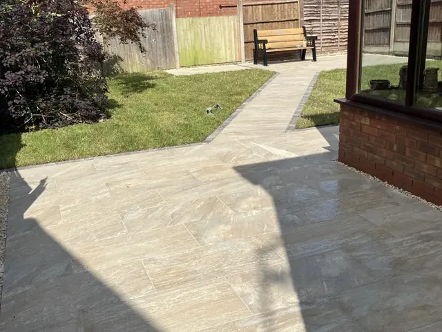 Natural stone patio and path running alongside a lawn