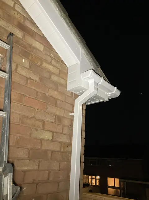 New white fascia, soffit, guttering and downpipe on the corner of a brick house